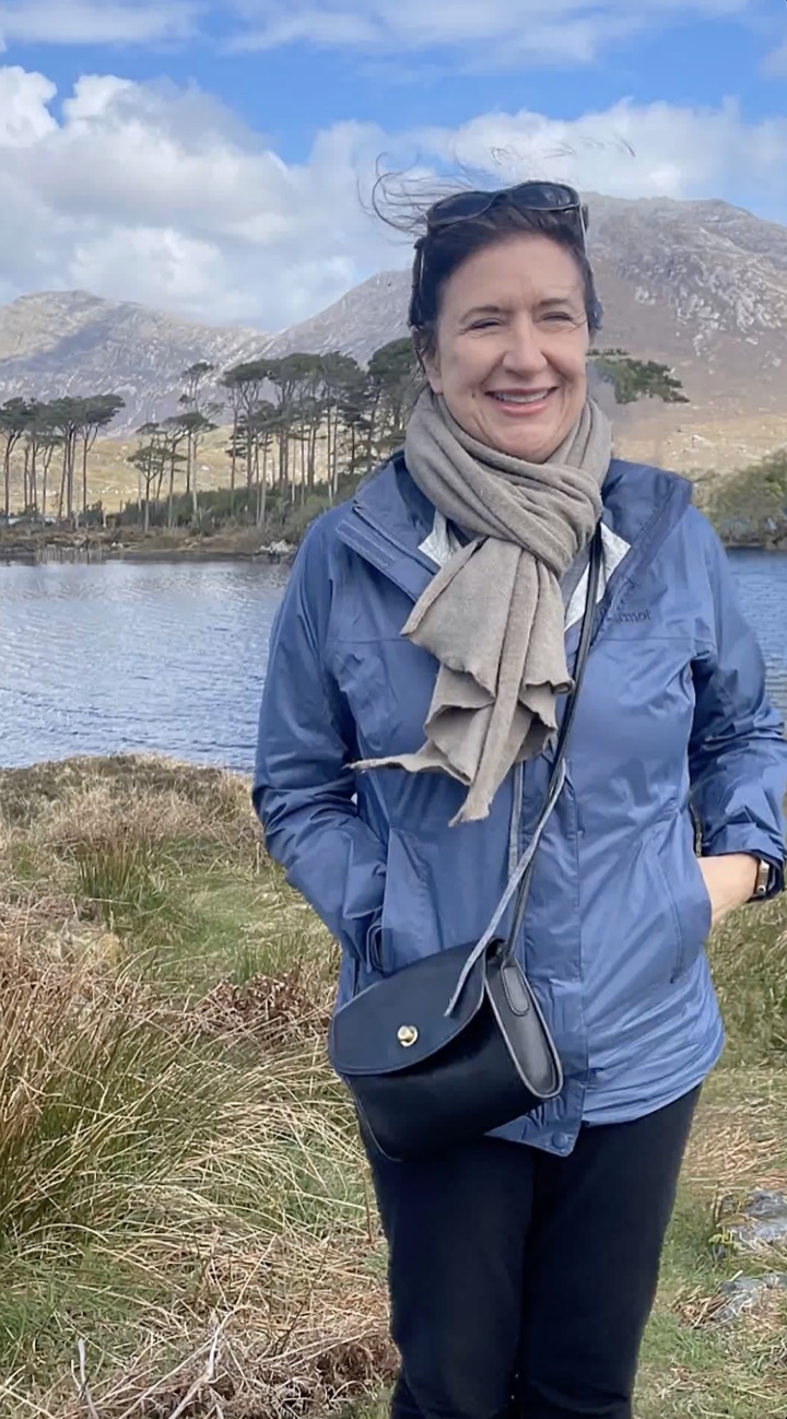 Teresa R. Foster smiling beside a mountain lake on a breezy day